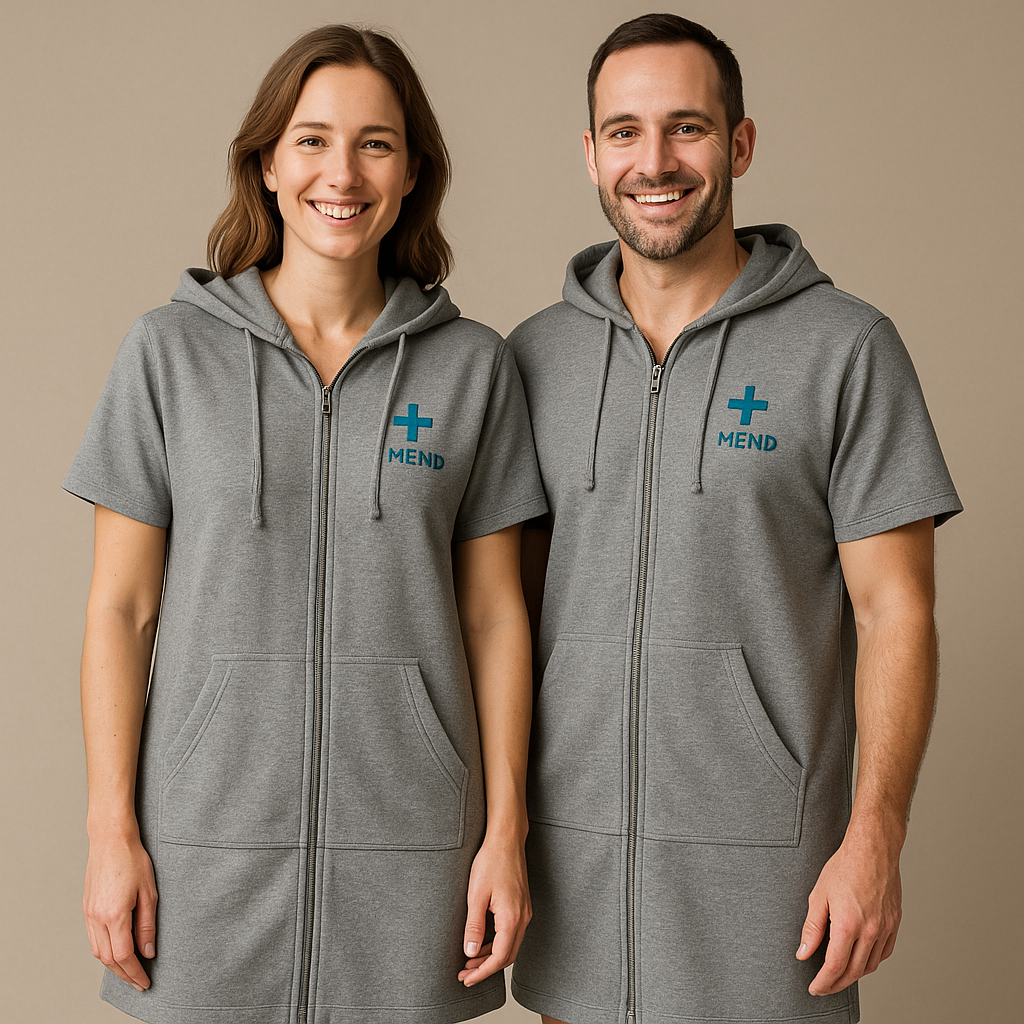 A woman and a man together, both wearing MEND Comfort Wrap recovery gowns